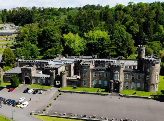 Aerial view of Cyfarthfa Castle amid woodland and parking area