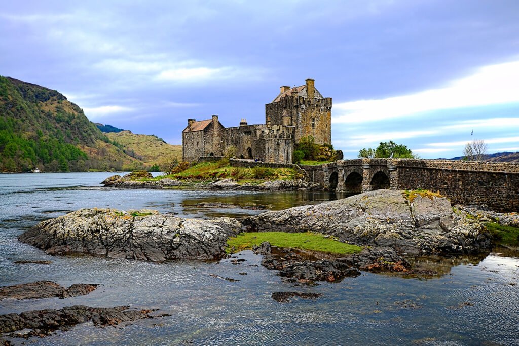 Eilean Donan Castle on rocky islet with arched stone bridge and calm loch