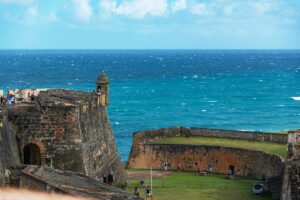 El Morro fortress walls overlooking turquoise Caribbean sea, visitors on ramparts