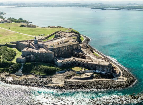 Aerial view of El Morro fortress on rocky headland with turquoise ocean