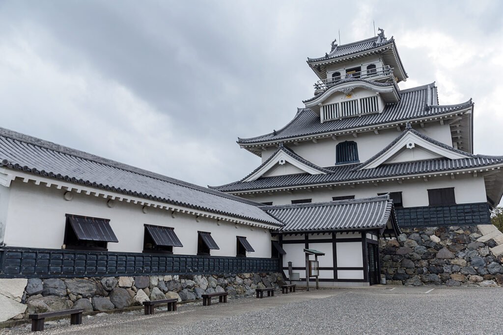 Hikone Castle tower and white walls under cloudy sky