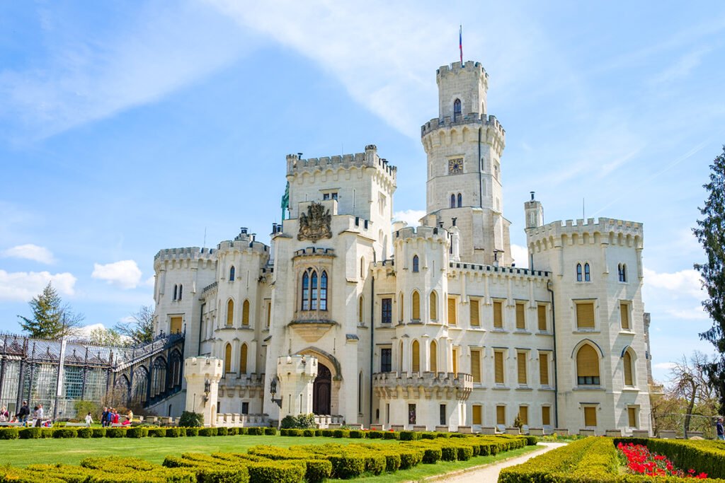 Hluboká Castle facade with trimmed hedges and bright blue sky