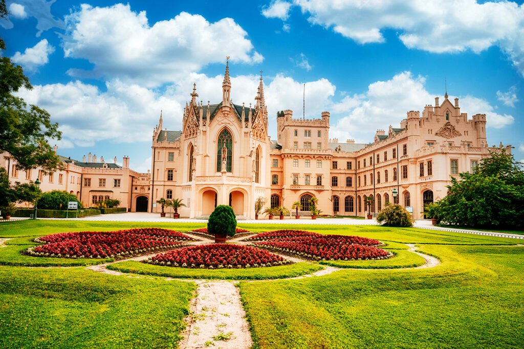 Front view of Lednice Castle with formal flowerbeds and blue sky