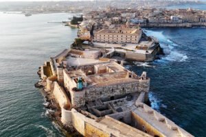 Aerial view of Maniace Castle fortress on rocky Syracuse promontory by the sea