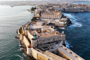 Aerial view of Maniace Castle fortress on rocky Syracuse promontory by the sea