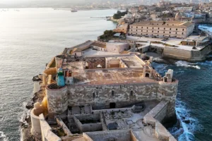 Aerial view of Maniace Castle on rocky Syracuse promontory at sunset