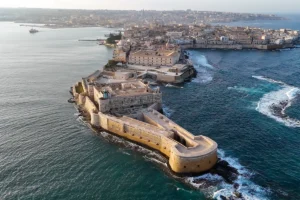 Aerial view of Maniace Castle on Ortigia peninsula, Syracuse, surrounded by turquoise sea