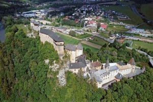 Aerial view of Orava Castle perched on rocky hillside above river and town