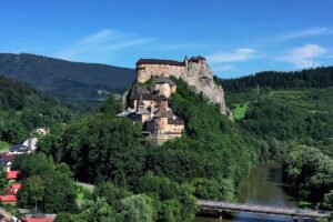 Orava Castle perched on a forested cliff above the river