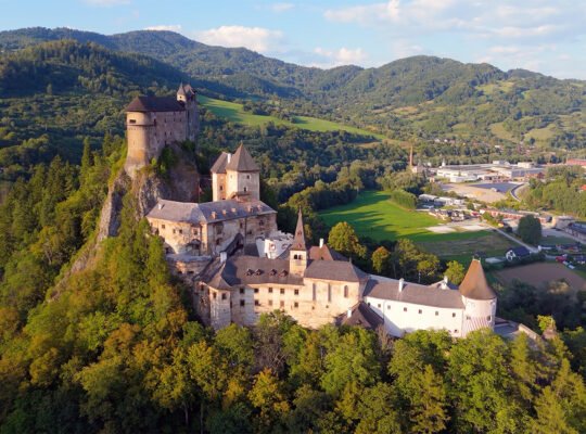 Aerial view of Orava Castle on rocky hill, forested valley