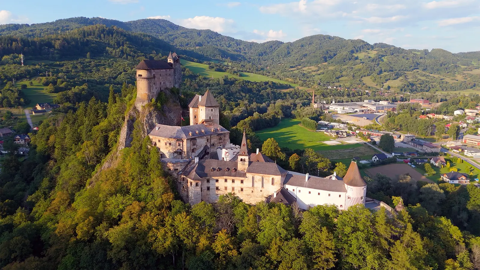 Aerial view of Orava Castle on rocky hill, forested valley