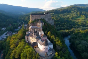Orava Castle on rocky hill beside winding river and forest