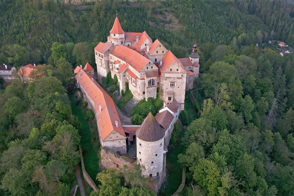 Aerial view of Pernštejn Castle perched in a forested landscape