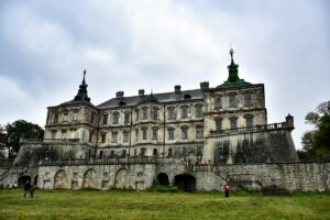 Pidhirtsi Castle façade with cloudy sky and grassy foreground