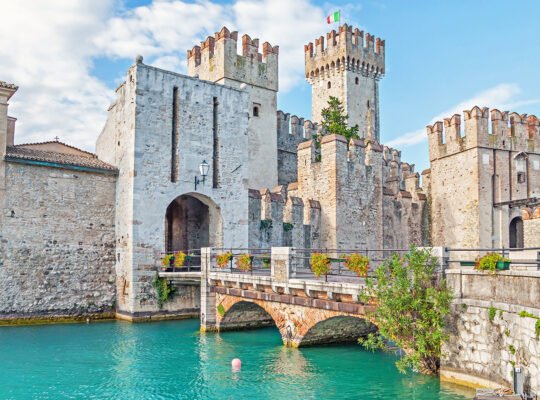 Sirmione Castle stone towers and bridge over turquoise Lake Garda