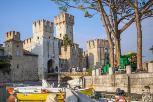 Sirmione Castle towers beside boats at sunny Lake Garda harbor