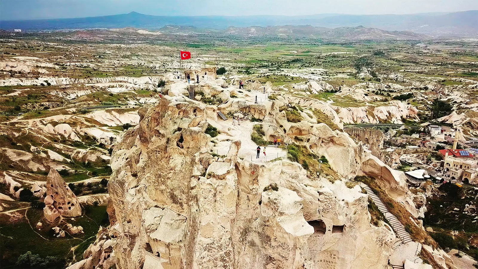 Aerial view of Uçhisar Castle overlooking Cappadocia valley with Turkish flag