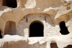 Uçhisar Castle stone-carved arched entrance and cave openings in sunlit tuff rock