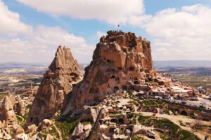 Uçhisar Castle atop carved rock with panoramic Cappadocia landscape beneath