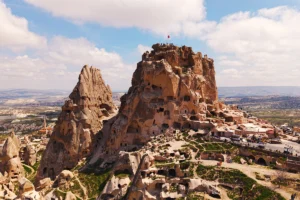 Uçhisar Castle atop carved rock with panoramic Cappadocia landscape beneath
