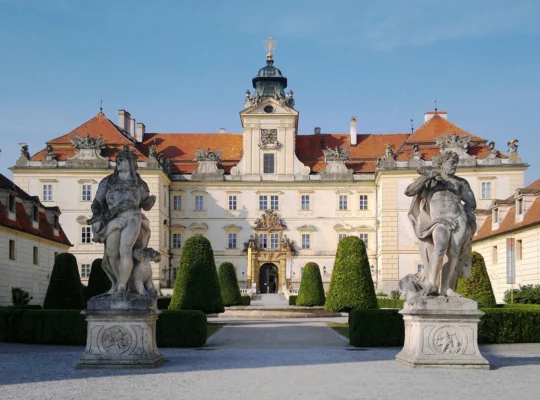 Front facade of Valtice Castle with statues and formal garden