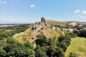 Aerial view of Corfe Castle ruins atop green hill