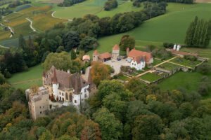 Aerial view of Gorgier Castle amid trees and rolling vineyards