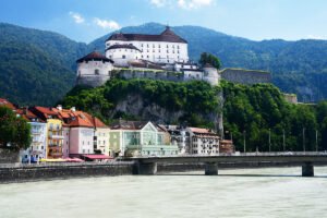 Kufstein Fortress on rocky hill above colorful riverside houses and bridge