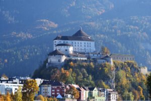 Kufstein Fortress on hill above colorful town and forested mountains