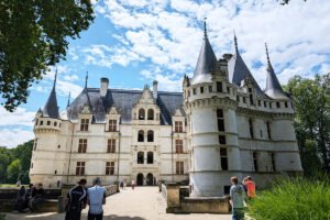 Azay‑le‑Rideau facade and towers reflected in moat, visitors approaching