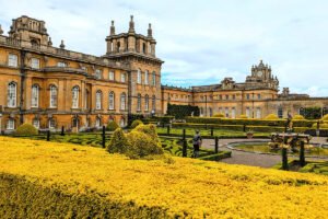 Blenheim Palace exterior with formal gardens and fountain under cloudy sky