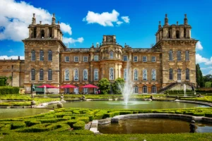 Blenheim Palace front facade with fountain and formal gardens on sunny day