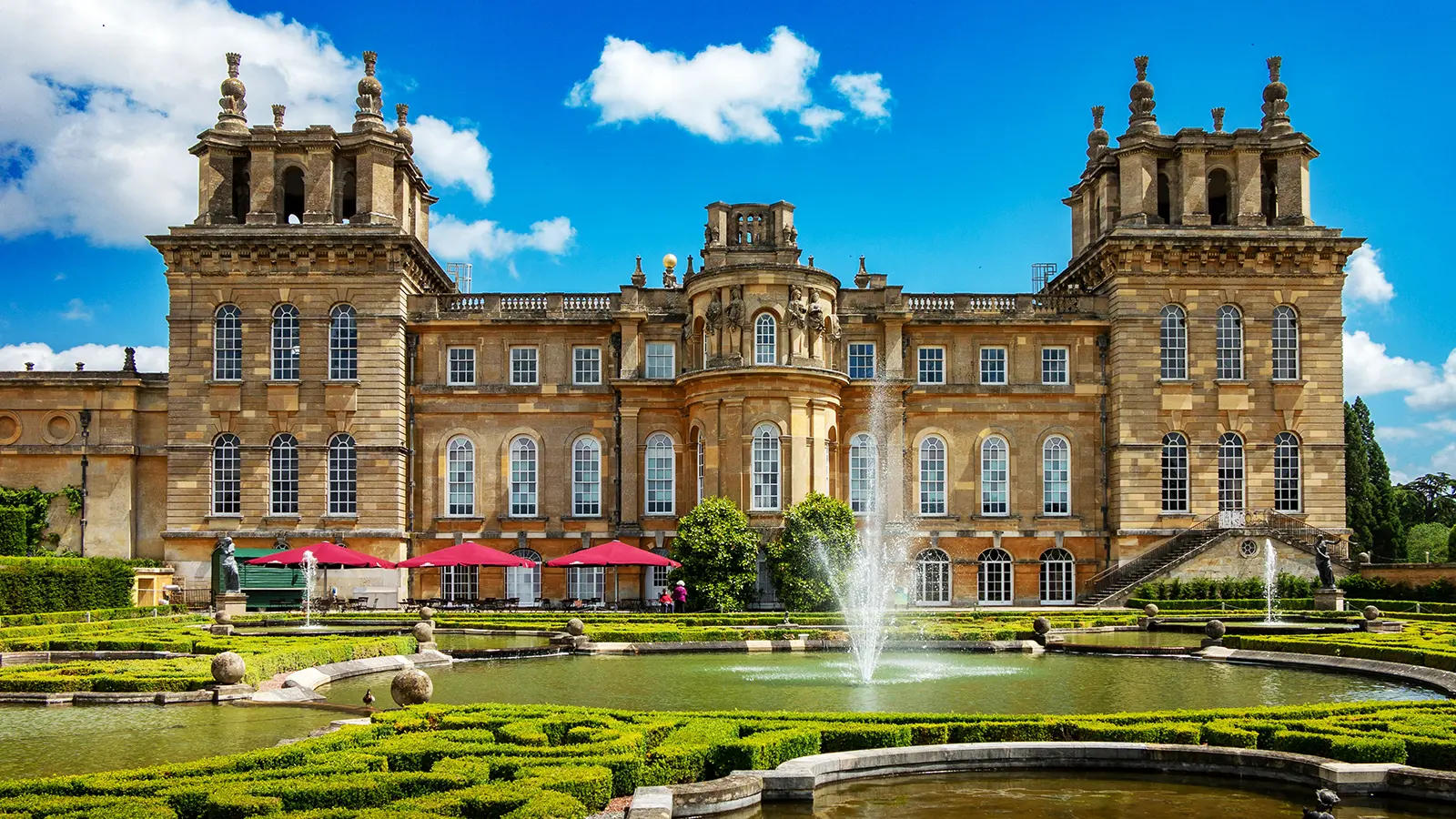 Blenheim Palace façade and formal water gardens under blue sky