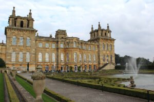 Blenheim Palace exterior with formal gardens and central fountain under overcast sky