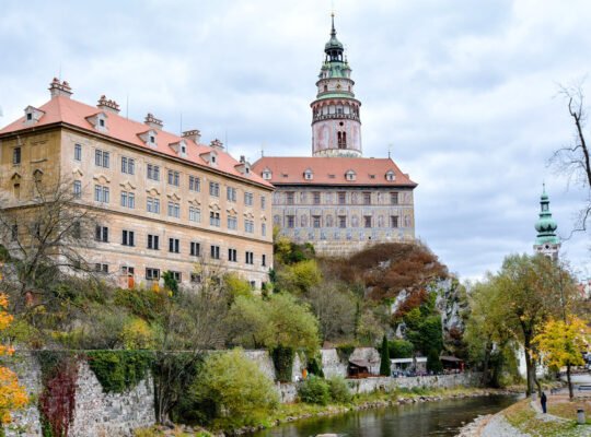 Cesky Krumlov Castle perched above river with autumn trees and tower