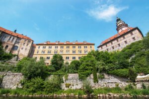 Cesky Krumlov Castle facade above river and greenery on sunny day
