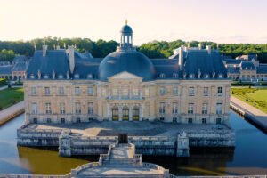 Aerial view of Château de Vaux-le-Vicomte over moat and gardens at golden hour