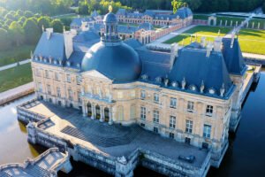Aerial view of Château de Vaux-le-Vicomte with gardens and moat at golden hour