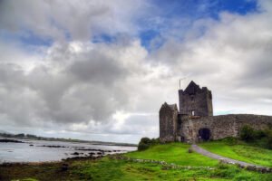 Dunguaire Castle beside rocky Galway Bay under cloudy sky