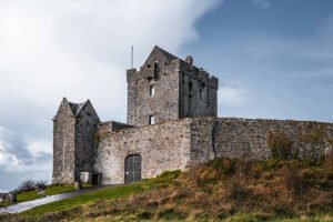 Dunguaire Castle tower and stone walls against cloudy sky