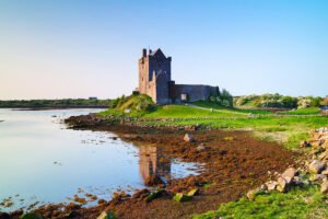 Dunguaire Castle beside calm tidal waters and rocky shore