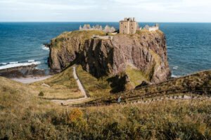 Dunnottar Castle perched on rugged sea cliffs with coastal path below