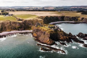 Aerial view of Dunnottar Castle perched on sea cliffs and rocky shoreline