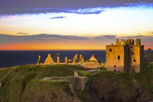 Dunnottar Castle ruins on cliff at sunset
