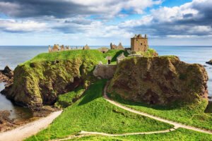 Dunnottar Castle perched on rugged coastal cliffs under blue sky