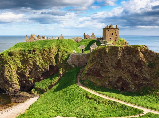 Clifftop ruins of Dunnottar Castle overlooking North Sea and grassy headland