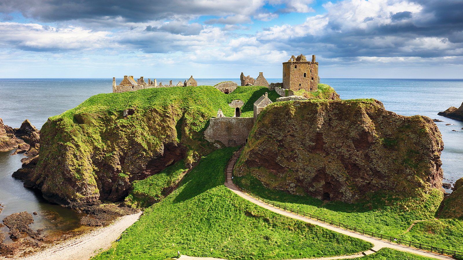 Clifftop ruins of Dunnottar Castle overlooking North Sea and grassy headland