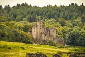 Dunvegan Castle amid green trees and rocky shore
