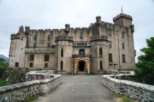 Front view of Dunvegan Castle with stone bridge and cloudy sky