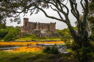 Dunvegan Castle on rocky shore framed by trees